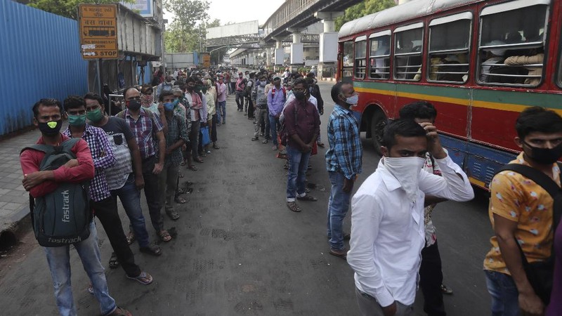 People wearing masks queue up to board buses in Mumbai, India, Monday, April 5, 2021. India reported its biggest single-day spike in confirmed coronavirus cases since the pandemic began Monday, and officials in the hard-hit state home to Mumbai are returning to the closure of some businesses and places of worship in a bid to slow the spread. (AP Photo/Rafiq Maqbool)