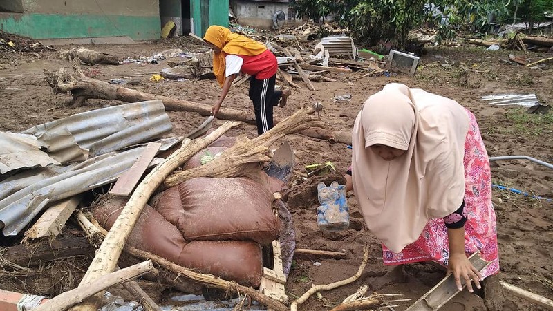 People watch as an excavator clears debris at a flood-affected area in Waiwerang, on Adonara Island, East Nusa Tenggara province, Indonesia, Tuesday, April 6, 2021. Rescuers in remote eastern Indonesia were digging through the debris of a landslide Tuesday in search of people believed to be buried in one of several disasters brought on by severe weather in the Southeast Asian nation and neighboring East Timor. (AP Photo/Rofinus Monteiro)