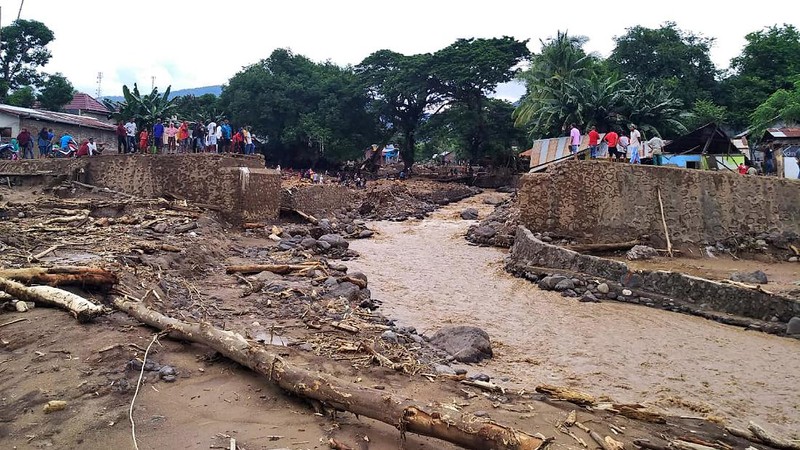 People watch as an excavator clears debris at a flood-affected area in Waiwerang, on Adonara Island, East Nusa Tenggara province, Indonesia, Tuesday, April 6, 2021. Rescuers in remote eastern Indonesia were digging through the debris of a landslide Tuesday in search of people believed to be buried in one of several disasters brought on by severe weather in the Southeast Asian nation and neighboring East Timor. (AP Photo/Rofinus Monteiro)