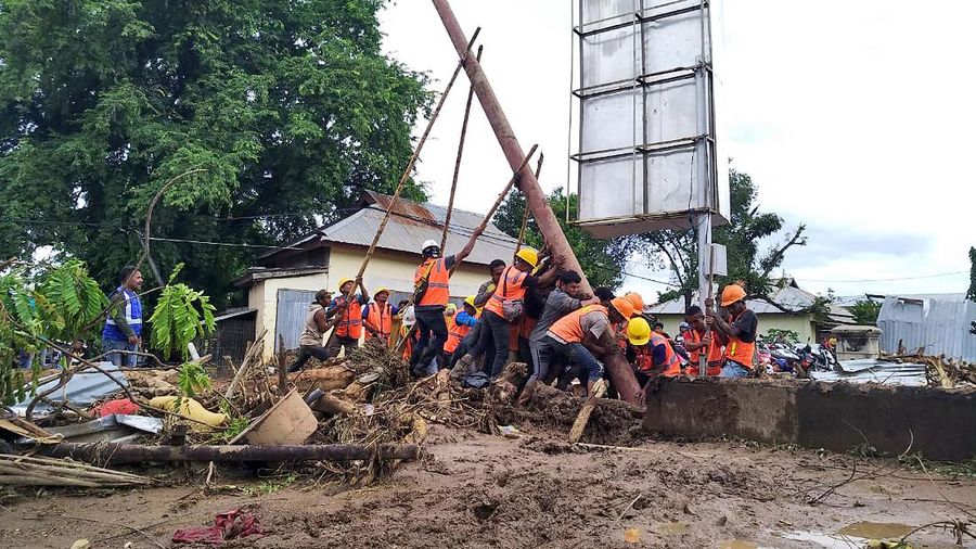People watch as an excavator clears debris at a flood-affected area in Waiwerang, on Adonara Island, East Nusa Tenggara province, Indonesia, Tuesday, April 6, 2021. Rescuers in remote eastern Indonesia were digging through the debris of a landslide Tuesday in search of people believed to be buried in one of several disasters brought on by severe weather in the Southeast Asian nation and neighboring East Timor. (AP Photo/Rofinus Monteiro)