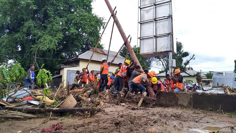 People watch as an excavator clears debris at a flood-affected area in Waiwerang, on Adonara Island, East Nusa Tenggara province, Indonesia, Tuesday, April 6, 2021. Rescuers in remote eastern Indonesia were digging through the debris of a landslide Tuesday in search of people believed to be buried in one of several disasters brought on by severe weather in the Southeast Asian nation and neighboring East Timor. (AP Photo/Rofinus Monteiro)