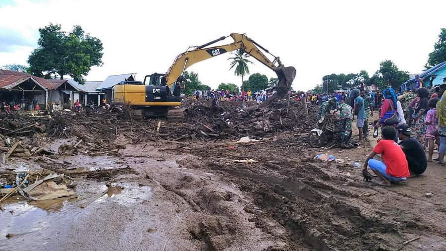 People watch as an excavator clears debris at a flood-affected area in Waiwerang, on Adonara Island, East Nusa Tenggara province, Indonesia, Tuesday, April 6, 2021. Rescuers in remote eastern Indonesia were digging through the debris of a landslide Tuesday in search of people believed to be buried in one of several disasters brought on by severe weather in the Southeast Asian nation and neighboring East Timor. (AP Photo/Rofinus Monteiro)