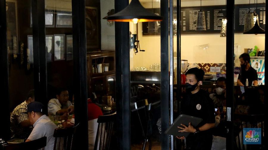 Petugas membersihkan meja makanan di Restoran di Kawasan Benhil, Jakarta, Selasa 6/4. Perhimpunan Hotel dan Restoran Indonesia (PHRI) Jakarta ingin pemerintah meningkatkan kapasitas jumlah pengunjung yang bisa makan di tempat alias dine in di tempat makan menjadi 75 persen saat masa buka bersama (bukber) puasa sepanjang Ramadan. Saat ini, kapasitas pengunjung dine in hanya boleh 50 persen. Kebijakan ini diterapkan karena pemerintah masih melangsungkan Pemberlakuan Pembatasan Kegiatan Masyarakat (PPKM) Mikro. Terkait hal ini, Pelaksana Tugas (Plt) Kepala Dinas Pariwisata dan Ekonomi Kreatif DKI Jakarta Gumilar Ekalaya mengatakan belum ada perubahan aturan terkait kapasitas jam operasional restoran saat momen buka puasa bersama seperti dikutip CNN Indonesia. Namun, pemerintah tetap membuka masukan dari pengusaha. Pelaksana tugas (Plt) Kepala Dinas Pariwisata dan Ekonomi Kreatif DKI Jakarta, Gumilar Ekalaya juga mengatakan pihaknya tidak melarang pelaksanaan kegiatan buka puasa bersama (bukber) di restoran atau rumah makan di masa pandemi Covid-19. Menurut Gumilar, waktu pelaksanaan kegiatan bukber tidak melanggar ketentuan dalam PPKM Mikro. Meski tidak melarang, Gumilar mengingatkan kegiatan buka bersama harus tetap menerapkan protokol kesehatan. (CNBC Indonesia/Muhammad Sabki)