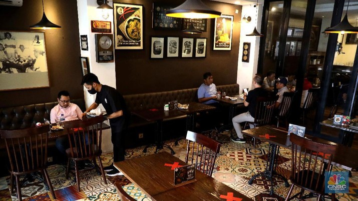 Petugas membersihkan meja makanan di Restoran di Kawasan Benhil, Jakarta, Selasa 6/4. Perhimpunan Hotel dan Restoran Indonesia (PHRI) Jakarta ingin pemerintah meningkatkan kapasitas jumlah pengunjung yang bisa makan di tempat alias dine in di tempat makan menjadi 75 persen saat masa buka bersama (bukber) puasa sepanjang Ramadan. Saat ini, kapasitas pengunjung dine in hanya boleh 50 persen. Kebijakan ini diterapkan karena pemerintah masih melangsungkan Pemberlakuan Pembatasan Kegiatan Masyarakat (PPKM) Mikro. Terkait hal ini, Pelaksana Tugas (Plt) Kepala Dinas Pariwisata dan Ekonomi Kreatif DKI Jakarta Gumilar Ekalaya mengatakan belum ada perubahan aturan terkait kapasitas jam operasional restoran saat momen buka puasa bersama seperti dikutip CNN Indonesia. Namun, pemerintah tetap membuka masukan dari pengusaha. Pelaksana tugas (Plt) Kepala Dinas Pariwisata dan Ekonomi Kreatif DKI Jakarta, Gumilar Ekalaya juga mengatakan pihaknya tidak melarang pelaksanaan kegiatan buka puasa bersama (bukber) di restoran atau rumah makan di masa pandemi Covid-19. Menurut Gumilar, waktu pelaksanaan kegiatan bukber tidak melanggar ketentuan dalam PPKM Mikro. Meski tidak melarang, Gumilar mengingatkan kegiatan buka bersama harus tetap menerapkan protokol kesehatan. (CNBC Indonesia/Muhammad Sabki)