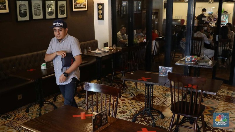 Petugas membersihkan meja makanan di Restoran di Kawasan Benhil, Jakarta, Selasa 6/4. Perhimpunan Hotel dan Restoran Indonesia (PHRI) Jakarta ingin pemerintah meningkatkan kapasitas jumlah pengunjung yang bisa makan di tempat alias dine in di tempat makan menjadi 75 persen saat masa buka bersama (bukber) puasa sepanjang Ramadan. Saat ini, kapasitas pengunjung dine in hanya boleh 50 persen. Kebijakan ini diterapkan karena pemerintah masih melangsungkan Pemberlakuan Pembatasan Kegiatan Masyarakat (PPKM) Mikro. Terkait hal ini, Pelaksana Tugas (Plt) Kepala Dinas Pariwisata dan Ekonomi Kreatif DKI Jakarta Gumilar Ekalaya mengatakan belum ada perubahan aturan terkait kapasitas jam operasional restoran saat momen buka puasa bersama seperti dikutip CNN Indonesia. Namun, pemerintah tetap membuka masukan dari pengusaha. Pelaksana tugas (Plt) Kepala Dinas Pariwisata dan Ekonomi Kreatif DKI Jakarta, Gumilar Ekalaya juga mengatakan pihaknya tidak melarang pelaksanaan kegiatan buka puasa bersama (bukber) di restoran atau rumah makan di masa pandemi Covid-19. Menurut Gumilar, waktu pelaksanaan kegiatan bukber tidak melanggar ketentuan dalam PPKM Mikro. Meski tidak melarang, Gumilar mengingatkan kegiatan buka bersama harus tetap menerapkan protokol kesehatan. (CNBC Indonesia/Muhammad Sabki)