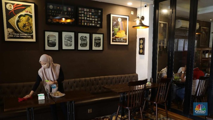 Ilustrasi Restoran Petugas membersihkan meja makanan di Restoran di Kawasan Benhil, Jakarta, Selasa 6/4. Perhimpunan Hotel dan Restoran Indonesia (PHRI) Jakarta ingin pemerintah meningkatkan kapasitas jumlah pengunjung yang bisa makan di tempat alias dine in di tempat makan menjadi 75 persen saat masa buka bersama (bukber) puasa sepanjang Ramadan. Saat ini, kapasitas pengunjung dine in hanya boleh 50 persen. Kebijakan ini diterapkan karena pemerintah masih melangsungkan Pemberlakuan Pembatasan Kegiatan Masyarakat (PPKM) Mikro. Terkait hal ini, Pelaksana Tugas (Plt) Kepala Dinas Pariwisata dan Ekonomi Kreatif DKI Jakarta Gumilar Ekalaya mengatakan belum ada perubahan aturan terkait kapasitas jam operasional restoran saat momen buka puasa bersama seperti dikutip CNN Indonesia. Namun, pemerintah tetap membuka masukan dari pengusaha. Pelaksana tugas (Plt) Kepala Dinas Pariwisata dan Ekonomi Kreatif DKI Jakarta, Gumilar Ekalaya juga mengatakan pihaknya tidak melarang pelaksanaan kegiatan buka puasa bersama (bukber) di restoran atau rumah makan di masa pandemi Covid-19. Menurut Gumilar, waktu pelaksanaan kegiatan bukber tidak melanggar ketentuan dalam PPKM Mikro. Meski tidak melarang, Gumilar mengingatkan kegiatan buka bersama harus tetap menerapkan protokol kesehatan. (CNBC Indonesia/Muhammad Sabki)