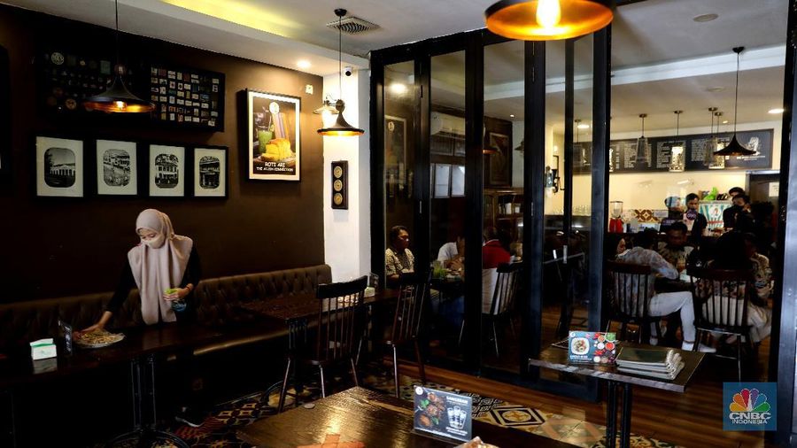 Petugas membersihkan meja makanan di Restoran di Kawasan Benhil, Jakarta, Selasa 6/4. Perhimpunan Hotel dan Restoran Indonesia (PHRI) Jakarta ingin pemerintah meningkatkan kapasitas jumlah pengunjung yang bisa makan di tempat alias dine in di tempat makan menjadi 75 persen saat masa buka bersama (bukber) puasa sepanjang Ramadan. Saat ini, kapasitas pengunjung dine in hanya boleh 50 persen. Kebijakan ini diterapkan karena pemerintah masih melangsungkan Pemberlakuan Pembatasan Kegiatan Masyarakat (PPKM) Mikro. Terkait hal ini, Pelaksana Tugas (Plt) Kepala Dinas Pariwisata dan Ekonomi Kreatif DKI Jakarta Gumilar Ekalaya mengatakan belum ada perubahan aturan terkait kapasitas jam operasional restoran saat momen buka puasa bersama seperti dikutip CNN Indonesia. Namun, pemerintah tetap membuka masukan dari pengusaha. Pelaksana tugas (Plt) Kepala Dinas Pariwisata dan Ekonomi Kreatif DKI Jakarta, Gumilar Ekalaya juga mengatakan pihaknya tidak melarang pelaksanaan kegiatan buka puasa bersama (bukber) di restoran atau rumah makan di masa pandemi Covid-19. Menurut Gumilar, waktu pelaksanaan kegiatan bukber tidak melanggar ketentuan dalam PPKM Mikro. Meski tidak melarang, Gumilar mengingatkan kegiatan buka bersama harus tetap menerapkan protokol kesehatan. (CNBC Indonesia/Muhammad Sabki)