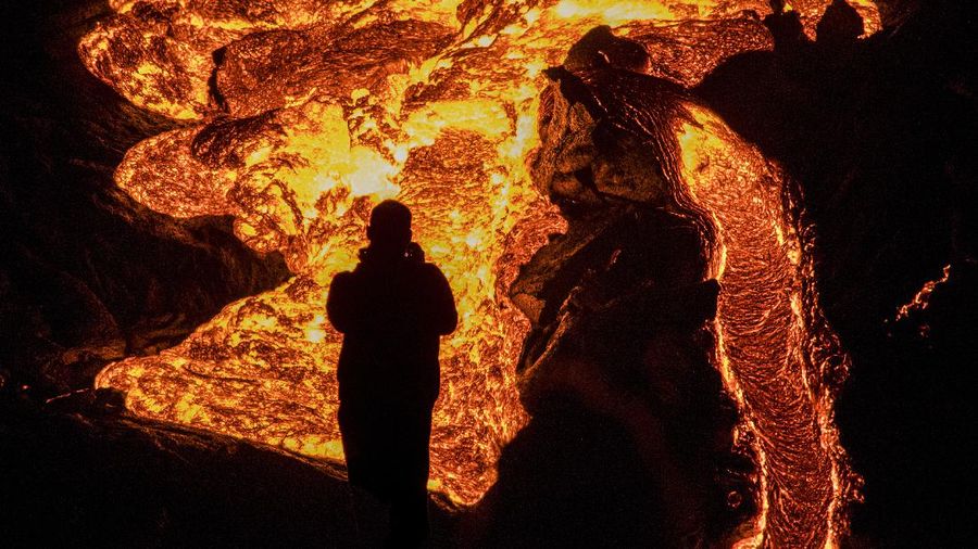 People watch as lava flows from an eruption of a volcano on the Reykjanes Peninsula in southwestern Iceland late on Monday, March 29, 2021. Iceland's latest volcano eruption is still attracting crowds of people hoping to get close to the gentle lava flows. (AP Photo/Marco Di Marco)