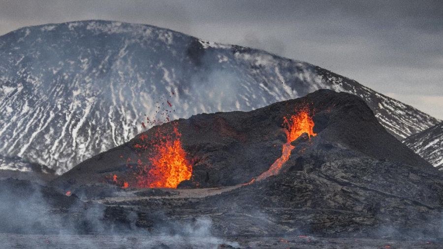 People watch as lava flows from an eruption of a volcano on the Reykjanes Peninsula in southwestern Iceland late on Monday, March 29, 2021. Iceland's latest volcano eruption is still attracting crowds of people hoping to get close to the gentle lava flows. (AP Photo/Marco Di Marco)
