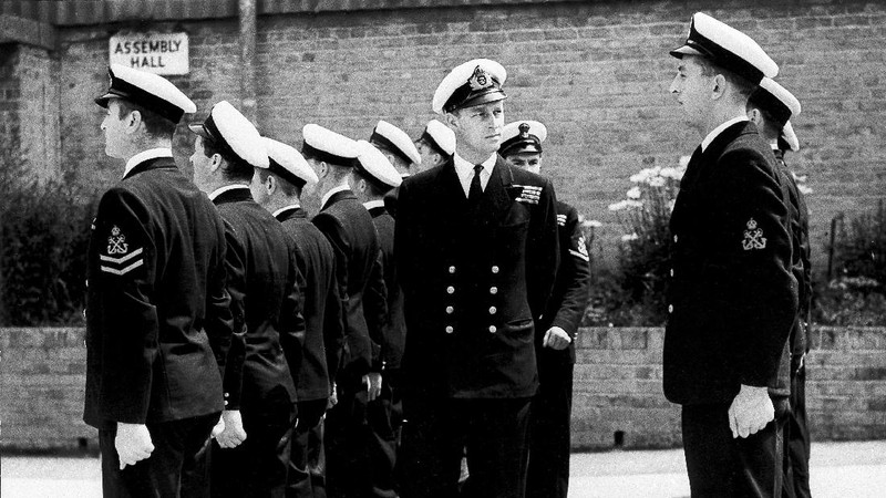 FILE - In this July 31, 1947 file photo, Lieut. Philip Mountbatten, as he was then called, center, inspects his men at the Petty Officers' Training Center at Corsham, England. There certainly won't be fuss. Count on that. When Britain's Prince Philip reaches the grand age of 99 on Wednesday, he will spend it quietly and in much the same way he's spent most of his adult life: beside Queen Elizabeth II. Prince Philip was born into the Greek royal family but spent almost all of his life as a pillar of the British one. His path was forged when he married the heir to the British throne, and a promising naval career was cut short when his wife suddenly became Queen Elizabeth II. Nevertheless, he set about forging a place for himself as royal consort. He was a patron of charities and a supporter of projects for young people. He was married for more than 73 years and was still carrying out royal engagements into his late 90s. (AP Photo/File)
