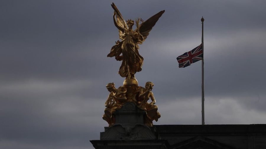 People view flowers left in front of the gate at Buckingham Palace in London, after the announcement of the death of Britain's Prince Philip, Friday, April 9, 2021. Buckingham Palace officials say Prince Philip, the husband of Queen Elizabeth II, has died. He was 99. Philip spent a month in hospital earlier this year before being released on March 16 to return to Windsor Castle. (AP Photo/Matt Dunham)