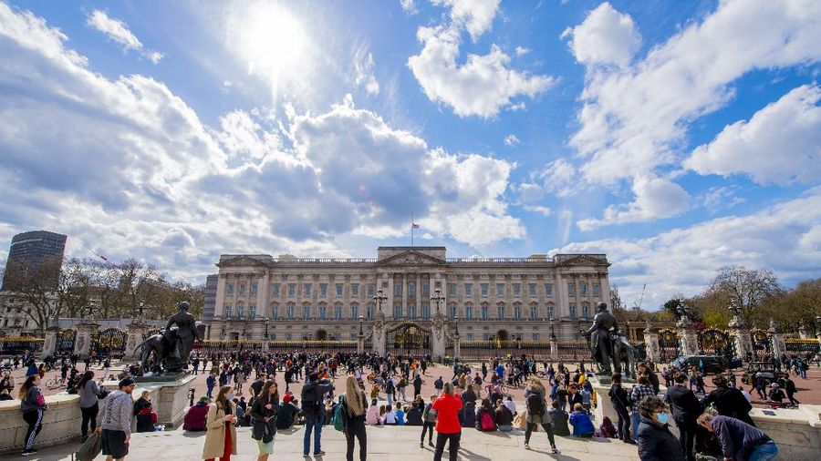 People view flowers left in front of the gate at Buckingham Palace in London, after the announcement of the death of Britain's Prince Philip, Friday, April 9, 2021. Buckingham Palace officials say Prince Philip, the husband of Queen Elizabeth II, has died. He was 99. Philip spent a month in hospital earlier this year before being released on March 16 to return to Windsor Castle. (AP Photo/Matt Dunham)