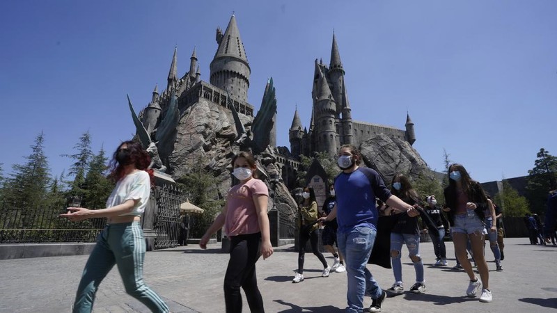 Young people wear mandatory face masks at the Wizarding World of Harry Potter at Universal Studios Hollywood theme park as it officially reopens to the public at 25% capacity with COVID-19 protocols in place in Los Angeles, Friday, April 16, 2021. (AP Photo/Damian Dovarganes)