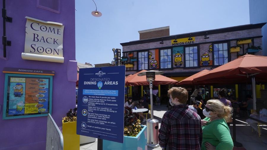 Young people wear mandatory face masks at the Wizarding World of Harry Potter at Universal Studios Hollywood theme park as it officially reopens to the public at 25% capacity with COVID-19 protocols in place in Los Angeles, Friday, April 16, 2021. (AP Photo/Damian Dovarganes)