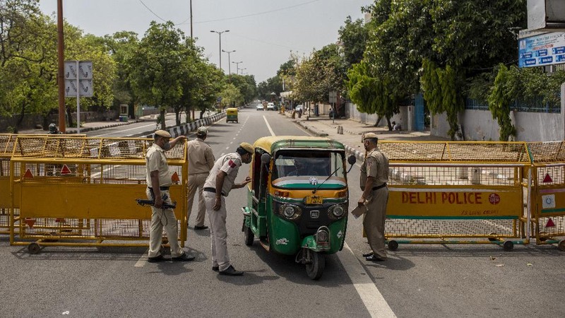 Delhi Police officers stop an autorickshaw at a check point during a weekend lockdown in New Delhi, India, Saturday, April 17, 2021. Over 200,000 new infections were detected in the past 24 hours, and major cities, like Mumbai and New Delhi, are under virus restrictions. (AP Photo/Altaf Qadri)