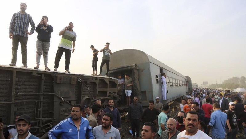 A crane is used to lift a part of a passenger train that derailed injuring some 100 people, near Banha, Qalyubia province, Egypt, Sunday, April 18, 2021. At least eight train wagons ran off the railway, the provincial governor's office said in a statement. (AP Photo/Fadel Dawood)
