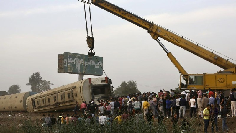 A crane is used to lift a part of a passenger train that derailed injuring some 100 people, near Banha, Qalyubia province, Egypt, Sunday, April 18, 2021. At least eight train wagons ran off the railway, the provincial governor's office said in a statement. (AP Photo/Fadel Dawood)