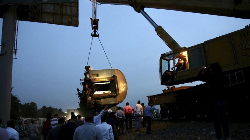 A crane is used to lift a part of a passenger train that derailed injuring some 100 people, near Banha, Qalyubia province, Egypt, Sunday, April 18, 2021. At least eight train wagons ran off the railway, the provincial governor's office said in a statement. (AP Photo/Fadel Dawood)
