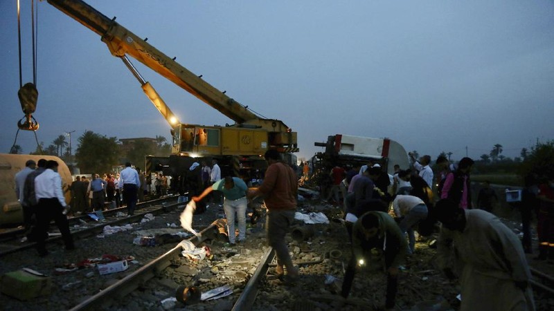 A crane is used to lift a part of a passenger train that derailed injuring some 100 people, near Banha, Qalyubia province, Egypt, Sunday, April 18, 2021. At least eight train wagons ran off the railway, the provincial governor's office said in a statement. (AP Photo/Fadel Dawood)