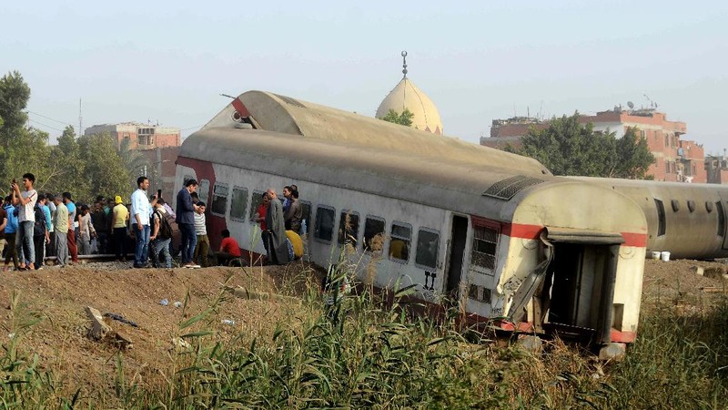 People gather at the site where a passenger train derailed injuring at least 100 people, near Banha, Qalyubia province, Egypt, Sunday, April 18, 2021. At least eight train wagons ran off the railway, the provincial governor's office said in a statement. (AP Photo/Tarek Wagih)