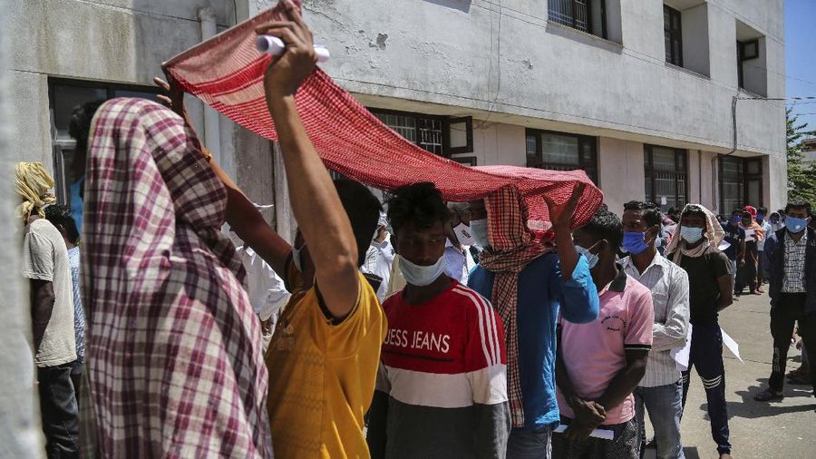 People wearing face masks as a precaution against the coronavirus line up without any physical distancing to get tested for COVID-19 at a government hospital in Jammu, India, Monday, April 19, 2021. India now has reported more than 15 million coronavirus infections, a total second only to the United States. (AP Photo/Channi Anand)