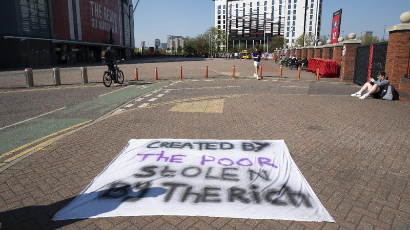 Football supporters place a protest banner outside Manchester United's Old Trafford Stadium, Manchester, England, Monday, April 19, 2021, opposing the formation of the European Super League. Players at the 12 clubs setting up their own Super League could be banned from this year’s European Championship and next year’s World Cup, UEFA President Aleksander Ceferin said Monday. (AP Photo/Jon Super)