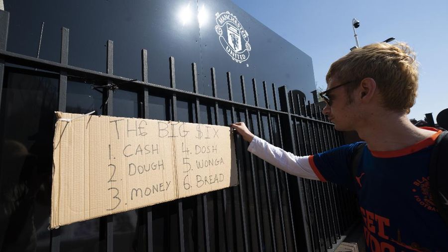 Football supporters place a protest banner outside Manchester United's Old Trafford Stadium, Manchester, England, Monday, April 19, 2021, opposing the formation of the European Super League. Players at the 12 clubs setting up their own Super League could be banned from this year’s European Championship and next year’s World Cup, UEFA President Aleksander Ceferin said Monday. (AP Photo/Jon Super)