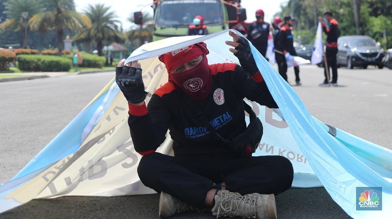 Sejumlah masa aksi buruh memakai hazmat dan membawa keranda mayat menggelar taterikal di Patung Kuda Arjuna Wiwaha, Jakarta, Rabu (21/4/2021). (CNBC Indonesia/Tri Susilo)