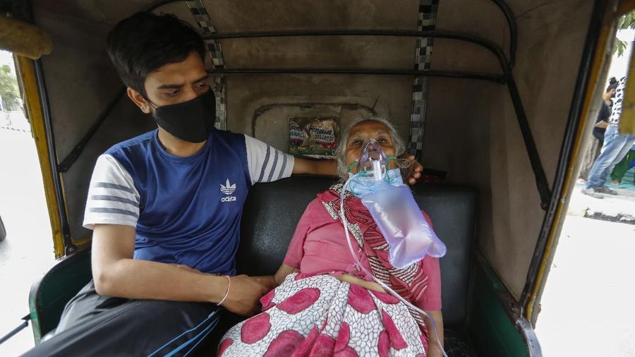 A COVID-19 patient wearing oxygen mask waits inside an auto ricksha to be attended and admitted to a dedicated COVID-19 government hospital in Ahmedabad, India, Saturday, April 17, 2021. The global death toll from the coronavirus topped a staggering 3 million people Saturday amid repeated setbacks in the worldwide vaccination campaign and a deepening crisis in places such as Brazil, India and France. (AP Photo/Ajit Solanki)