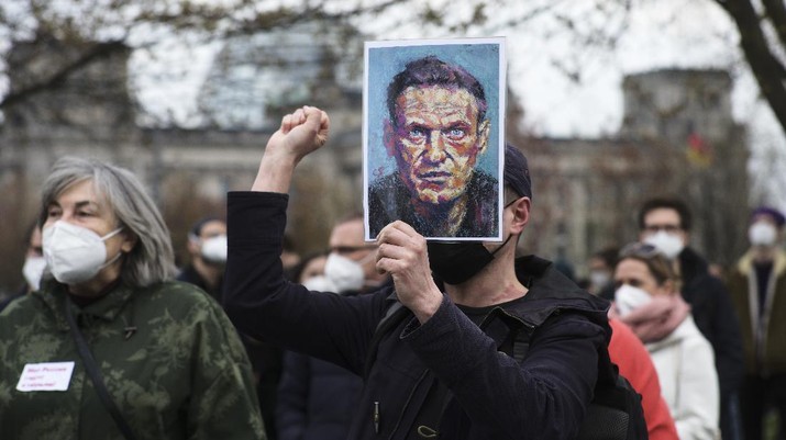 A man holds a poster with a drawing of Russian opposition leader Alexei Navalny, as he protests against the jailing of the Russian opposition leader near the chancellery in Berlin, Germany, Wednesday, April 21, 2021. In the background the Reichstag building with the German parliament. (AP Photo/Markus Schreiber)