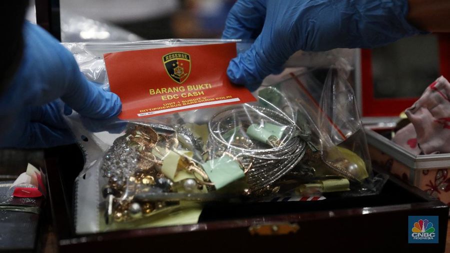 Petugas Bareskrim Polri merapihkan narang bukti hasil tindak pidana kasus dugaan penipuan investasi EDCCash saat gelar perkara di Bareskrim Polri , Jakarta, Kamis (22/4/2021). Total ada 6 orang ditetapkan sebagai tersangka, termasuk CEO EDCCash. (CNBC Indonesia/Andrean Kristianto)