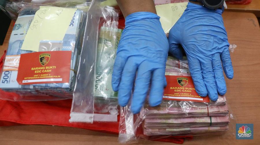 Petugas Bareskrim Polri merapihkan narang bukti hasil tindak pidana kasus dugaan penipuan investasi EDCCash saat gelar perkara di Bareskrim Polri , Jakarta, Kamis (22/4/2021). Total ada 6 orang ditetapkan sebagai tersangka, termasuk CEO EDCCash. (CNBC Indonesia/Andrean Kristianto)