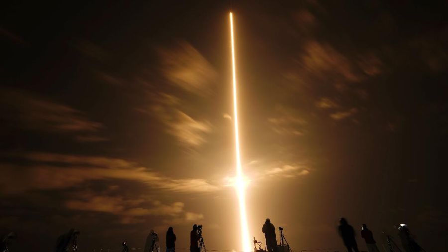 In this long exposure photo, photographers watch a SpaceX Falcon 9 rocket with the Crew Dragon space capsule lifts off from pad 39A at the Kennedy Space Center in Cape Canaveral, Fla., Friday, April 23, 2021. (AP Photo/Brynn Anderson)