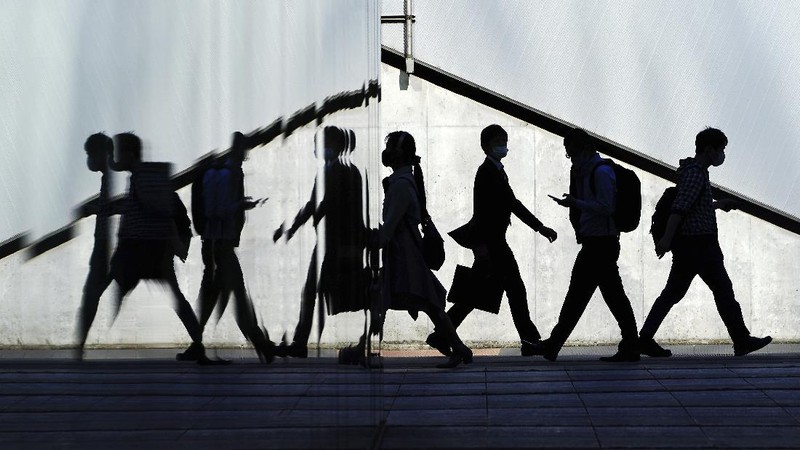 People wearing face masks to help curb the spread of the coronavirus walk towards a train station in Tokyo on Friday, April 23, 2021. (AP Photo/Hiro Komae)