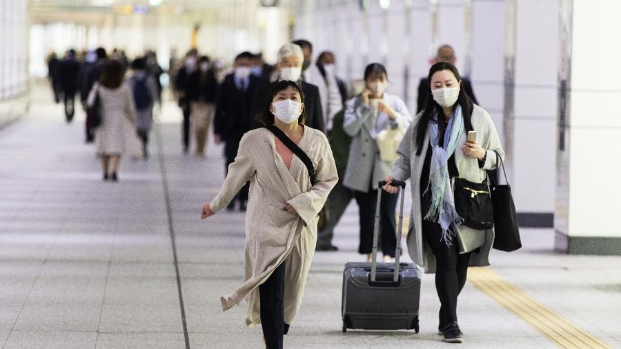 People wearing face masks to help curb the spread of the coronavirus walk towards a train station in Tokyo on Friday, April 23, 2021. (AP Photo/Hiro Komae)