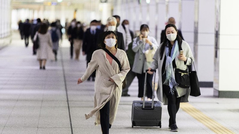 People wearing face masks to help curb the spread of the coronavirus walk towards a train station in Tokyo on Friday, April 23, 2021. (AP Photo/Hiro Komae)