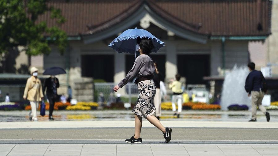 A woman wearing a protective mask to help curb the spread of the coronavirus walks at a park Wednesday, April 21, 2021, in Tokyo. The Japanese capital confirmed more than 840 new coronavirus cases on Wednesday. (AP Photo/Eugene Hoshiko)