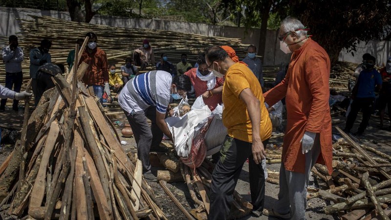 People perform rituals next to a funeral pyre for a family member who died of COVID-19 at a ground that has been converted into a crematorium for mass cremation of COVID-19 victims in New Delhi, India, Saturday, April 24, 2021. Delhi has been cremating so many bodies of coronavirus victims that authorities are getting requests to start cutting down trees in city parks, as a second record surge has brought India's tattered healthcare system to its knees. (AP Photo/Altaf Qadri)
