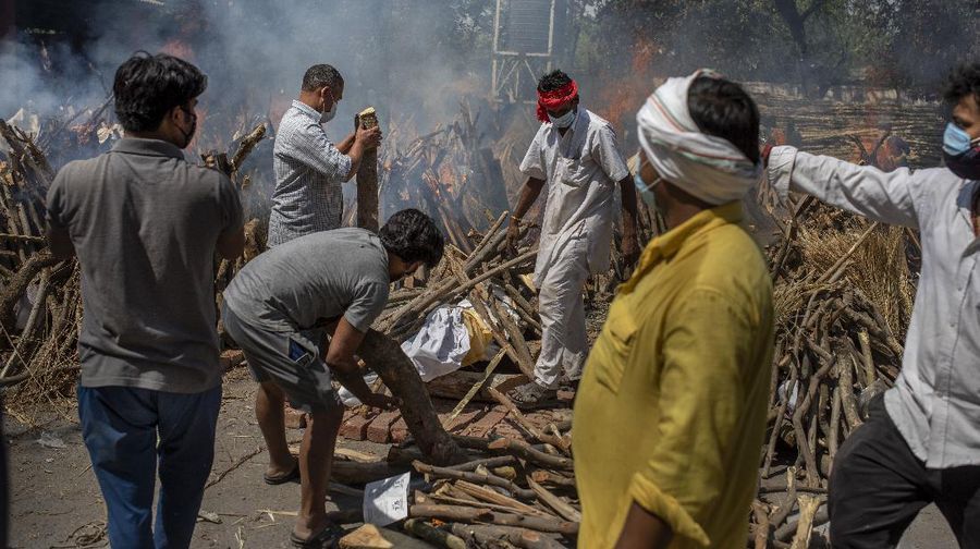 People perform rituals next to a funeral pyre for a family member who died of COVID-19 at a ground that has been converted into a crematorium for mass cremation of COVID-19 victims in New Delhi, India, Saturday, April 24, 2021. Delhi has been cremating so many bodies of coronavirus victims that authorities are getting requests to start cutting down trees in city parks, as a second record surge has brought India's tattered healthcare system to its knees. (AP Photo/Altaf Qadri)
