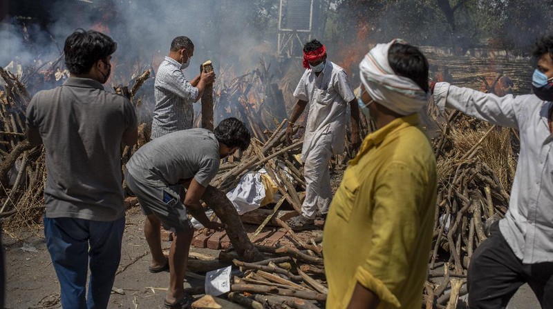 People perform rituals next to a funeral pyre for a family member who died of COVID-19 at a ground that has been converted into a crematorium for mass cremation of COVID-19 victims in New Delhi, India, Saturday, April 24, 2021. Delhi has been cremating so many bodies of coronavirus victims that authorities are getting requests to start cutting down trees in city parks, as a second record surge has brought India's tattered healthcare system to its knees. (AP Photo/Altaf Qadri)