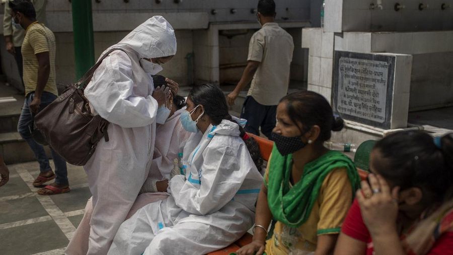 A woman is consoled by a relative at a crematorium during mass cremation of COVID-19 victims, in New Delhi, India, Saturday, April 24, 2021. Delhi has been cremating so many bodies of coronavirus victims that authorities are getting requests to start cutting down trees in city parks, as a second record surge has brought India's tattered healthcare system to its knees. (AP Photo/Altaf Qadri)