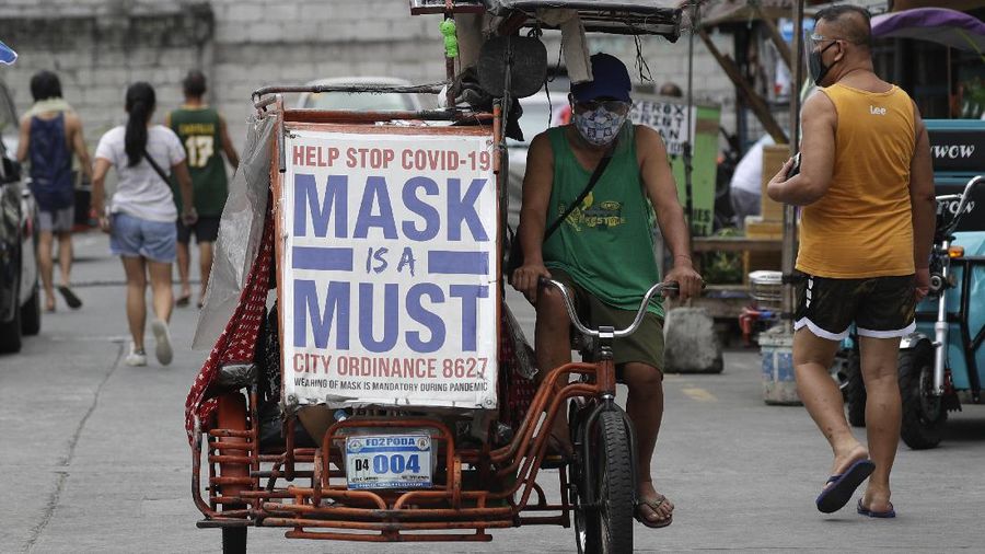 A man rides his pedicab with a slogan to remind people to wear masks to prevent the spread of the coronavirus in Manila, Philippines on Monday, April 26, 2021. COVID-19 infections in the Philippines surged past 1 million Monday in the latest grim milestone as officials assessed whether to extend a monthlong lockdown in Manila and outlying provinces amid a deadly spike or relax it to fight recession, joblessness and hunger. (AP Photo/Aaron Favila)