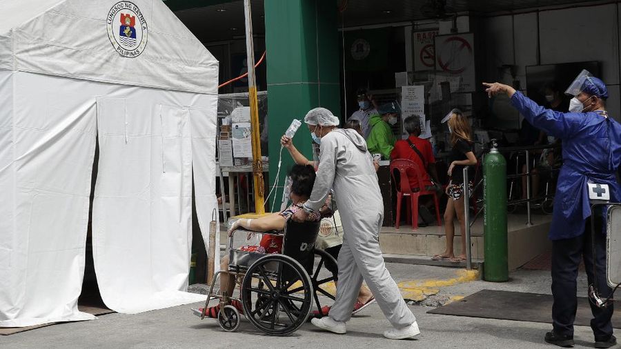 A man carries a sick woman from a pedicab as they bring her to the emergency area of the hospital that is crowded with suspected COVID-19 patients in Manila, Philippines on Monday, April 26, 2021. COVID-19 infections in the Philippines surged past 1 million Monday in the latest grim milestone as officials assessed whether to extend a monthlong lockdown in Manila and outlying provinces amid a deadly spike or relax it to fight recession, joblessness and hunger. (AP Photo/Aaron Favila)