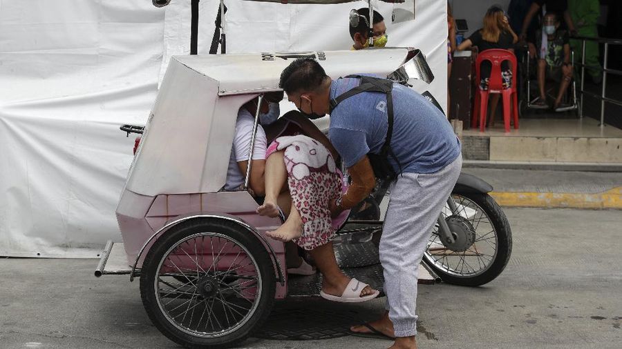 A man carries a sick woman from a pedicab as they bring her to the emergency area of the hospital that is crowded with suspected COVID-19 patients in Manila, Philippines on Monday, April 26, 2021. COVID-19 infections in the Philippines surged past 1 million Monday in the latest grim milestone as officials assessed whether to extend a monthlong lockdown in Manila and outlying provinces amid a deadly spike or relax it to fight recession, joblessness and hunger. (AP Photo/Aaron Favila)