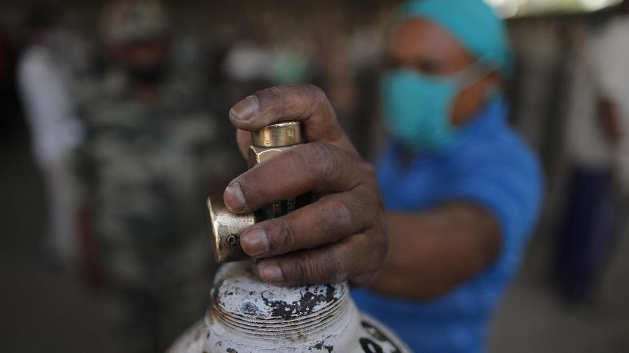 Seorang pria menunggu untuk mengisi tabung oksigen medis di stasiun pengisian di pinggiran Prayagraj, India, Jumat, 23 April 2021. (AP / Rajesh Kumar Singh)