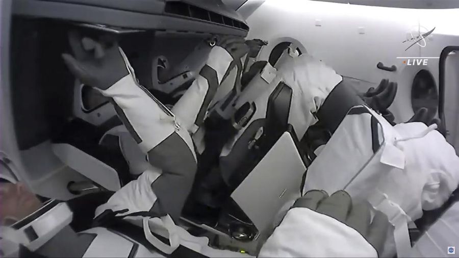 In this image made from NASA TV, crew members are seen in the SpaceX Crew Dragon spacecraft as it docks at the international space station, Saturday, April 24, 2021. The recycled SpaceX capsule carrying four astronauts has arrived at the International Space Station, a day after launching from Florida. (NASA via AP)