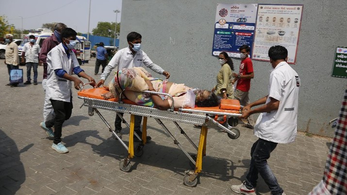 Petugas kesehatan membawa pasien untuk dirawat di rumah sakit pemerintah COVID-19 di Ahmedabad, India, Selasa, 27 April 2021. (AP / Ajit Solanki) Health workers bring a patient to be admitted at a government COVID-19 hospital in Ahmedabad, India, Tuesday, April 27, 2021. Coronavirus cases in India are surging faster than anywhere else in the world. (AP Photo/Ajit Solanki)