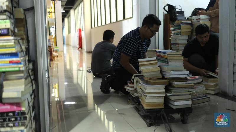 Sejumlah pedagang merapikan buku bacaan di Pasar Kenari, Jakarta, Kamis (29/4/2021). Pasar Buku Kenari sangat sepi dari pengunjung di tengah masa pandemi Covid-19. Pantauan CNBC Indonesia sesekali ada warga yang melihat - lihat bahkan membeli buku satu atau dua di Pasar ini. Pasar Buku Kenari menjual berbagai macam buku mulai buku bacaan hingga komik, buku yang dijual merupakan buku bekas ataupun buku baru. Novelia (19) mewakili pedagang buku yang terdampak pandemi covid mengatakan 