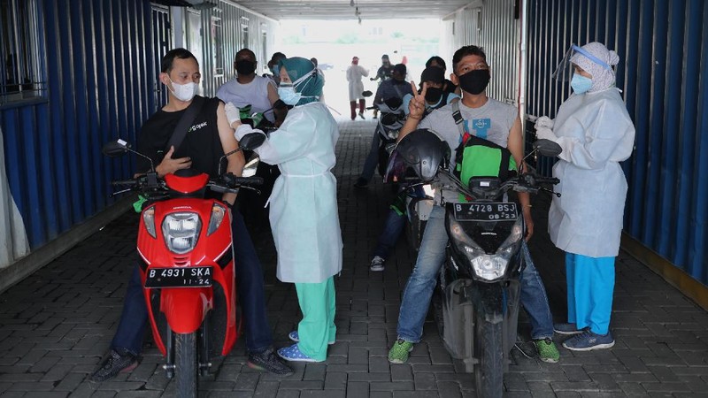 Petugas kesehatan menyuntikkan vaksin dosis pertama kepada driver Gojek di Kemayoran, Jakarta, Kamis (29/4/2021). Halodoc dan Gojek berkolaborasi hadirkan pos pelayanan Covid-19 melalui metode Drive thru dan melayani 1.500 dosis vaksin setiap harinya untuk memperkuat upaya Kementerian Kesehatan RI dalam mempercepat Vaksinasi Covid-19 di Indonesia.  (CNBC Indonesia/ Tri Susilo)