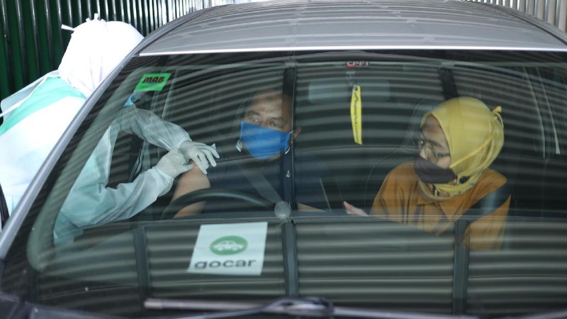Petugas kesehatan menyuntikkan vaksin dosis pertama kepada driver Gojek di Kemayoran, Jakarta, Kamis (29/4/2021). Halodoc dan Gojek berkolaborasi hadirkan pos pelayanan Covid-19 melalui metode Drive thru dan melayani 1.500 dosis vaksin setiap harinya untuk memperkuat upaya Kementerian Kesehatan RI dalam mempercepat Vaksinasi Covid-19 di Indonesia.  (CNBC Indonesia/ Tri Susilo)